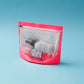 a neon pink gusseted pouch with clear front and zipper closure revealing contents of disposable masks and small hand sanitizer bottles